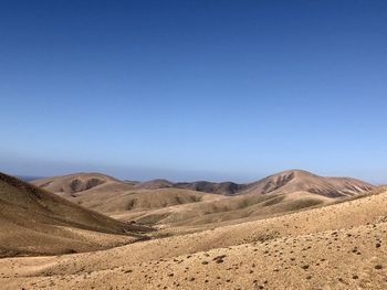 Scenic view of desert against clear blue sky