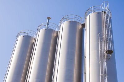 Low angle view of silos against clear sky