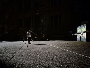 Full length of woman walking on illuminated street at night