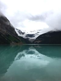 Scenic view of lake and mountains against cloudy sky