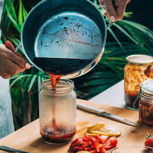 Fruit canning at home. woman pouring cooked jam into sterile jars. fruit preservation.