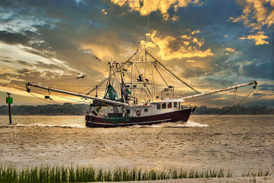 Sailboat moored on sea against sky during sunset