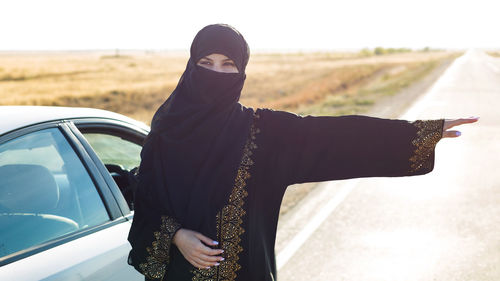 An islamic woman approaches a car and on a track. person
