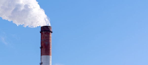 Smoke emitting from chimney against blue sky
