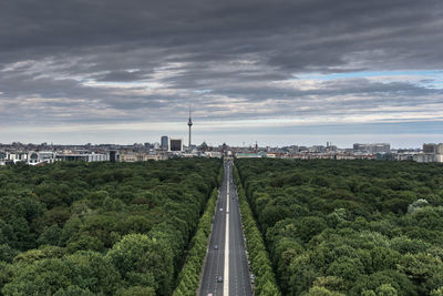 High angle view of treelined road leading to city