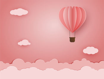 Hot air balloons flying over pink background