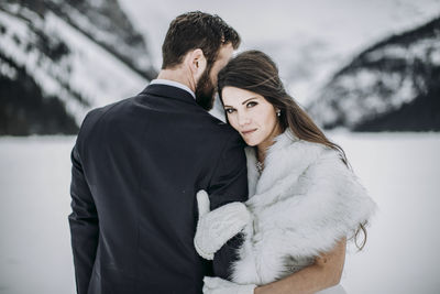 Bride in wedding dress grasps groom's arm after married on frozen lake