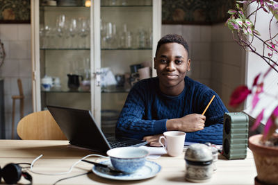 Portrait of confident smiling teenage boy doing homework at table