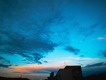 Low angle view of silhouette buildings against blue sky