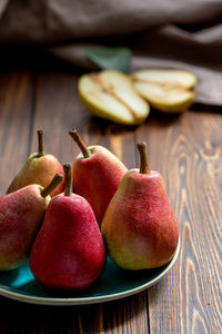 Ripe red pears on a blue plate on a wooden table . close up.