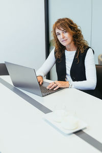 Portrait of young businesswoman using laptop at desk in office