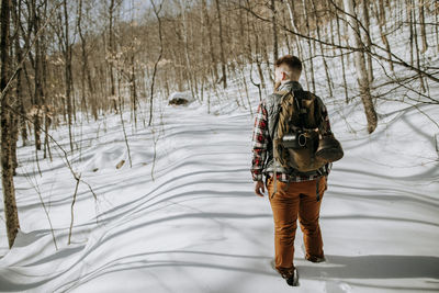 Man with canvas pack hikes through deep snow in the maine woods