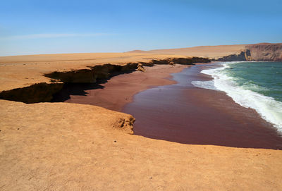 The red beach or playa roja with white wave foam from the pacific ocean, paracas, ica, peru