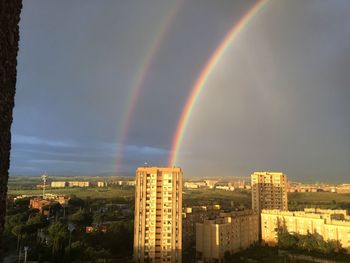 Rainbow over buildings in city against sky