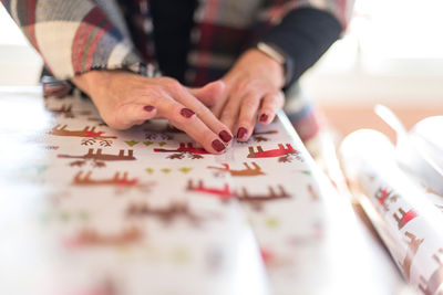 Midsection of woman wrapping gift at home