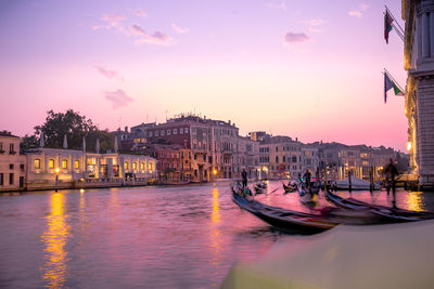 Canal amidst buildings in city at sunset