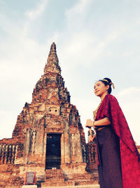 Low angle view of woman standing outside temple against sky