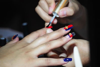 Cropped hand of beautician applying nail polish to woman