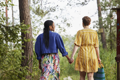 Female couple holding hands in forest