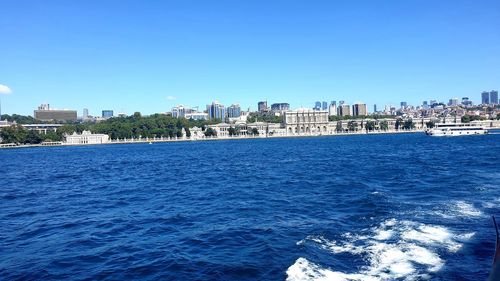 Sea by buildings against blue sky