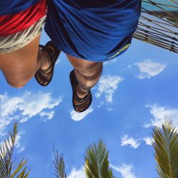 Low section of man with umbrella against sky