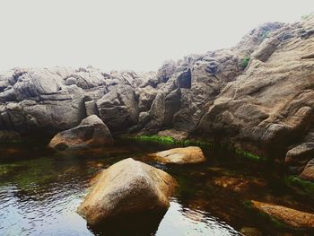 Rock formations in water against clear sky