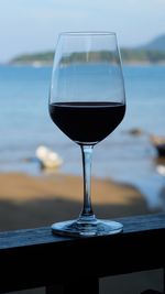 Close-up of wineglass on table by sea