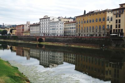 Bridge over canal by buildings against sky in city