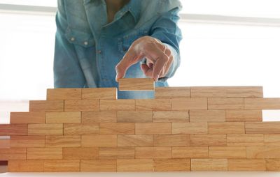 Midsection of man arranging wooden blocks at home