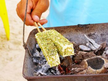 Cropped hand preparing cheese on barbecue