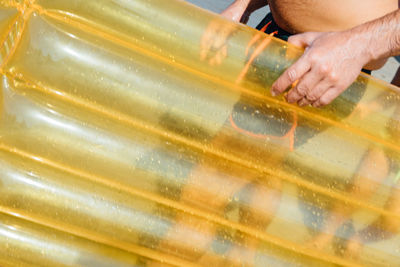 Low section of man with pool raft at beach