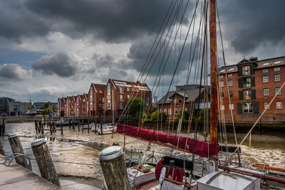 Sailboats moored at harbor against buildings in city