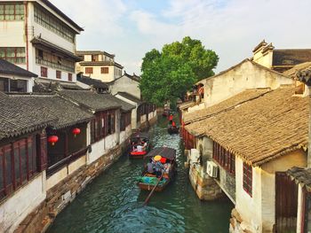 High angle view of people on boats sailing at canal amidst houses