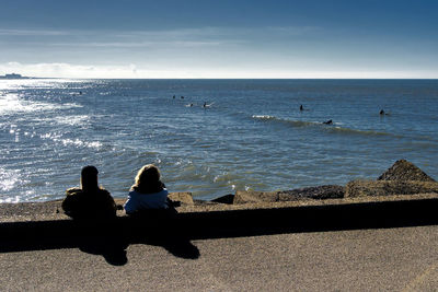 Rear view of women sitting on beach