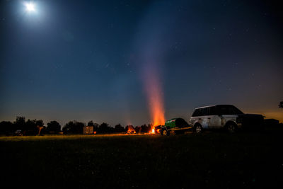 Cars on illuminated road against sky at night