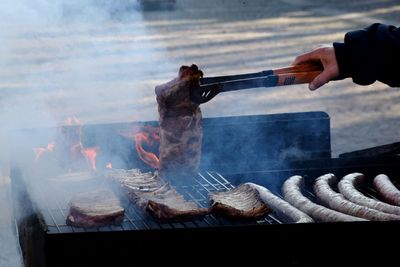 Close-up of hand preparing food on barbecue grill