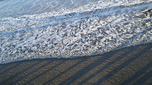 Close-up of snow on beach against sky