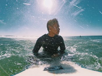 Man splashing water in sea against sky