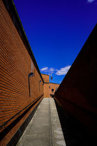 Empty alley amidst buildings against blue sky