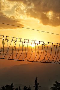 Silhouette fence against sky during sunset