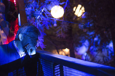 Mid adult man on balcony in light at night