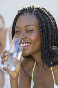 Close-up portrait of a smiling young woman drinking glass