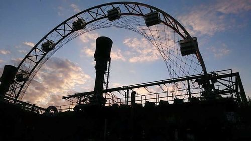 Silhouette amusement park ride against sky