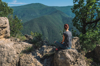Man sitting on rock against mountains
