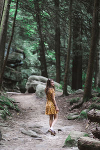 Full length of woman standing amidst trees in forest