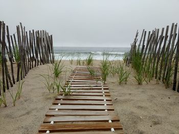 Wooden posts on beach against sky