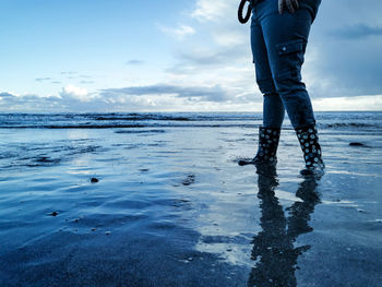 Low section of man standing on beach