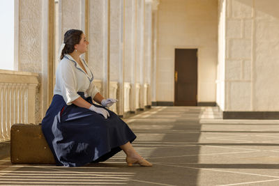 Side view of woman sitting on footpath