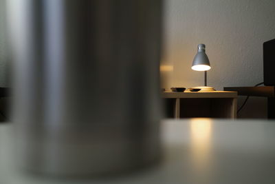 Close-up of electric lamp on table against wall at home