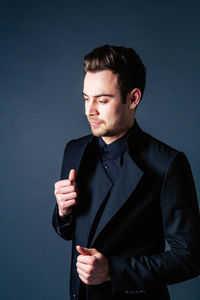 Portrait of young man standing against black background